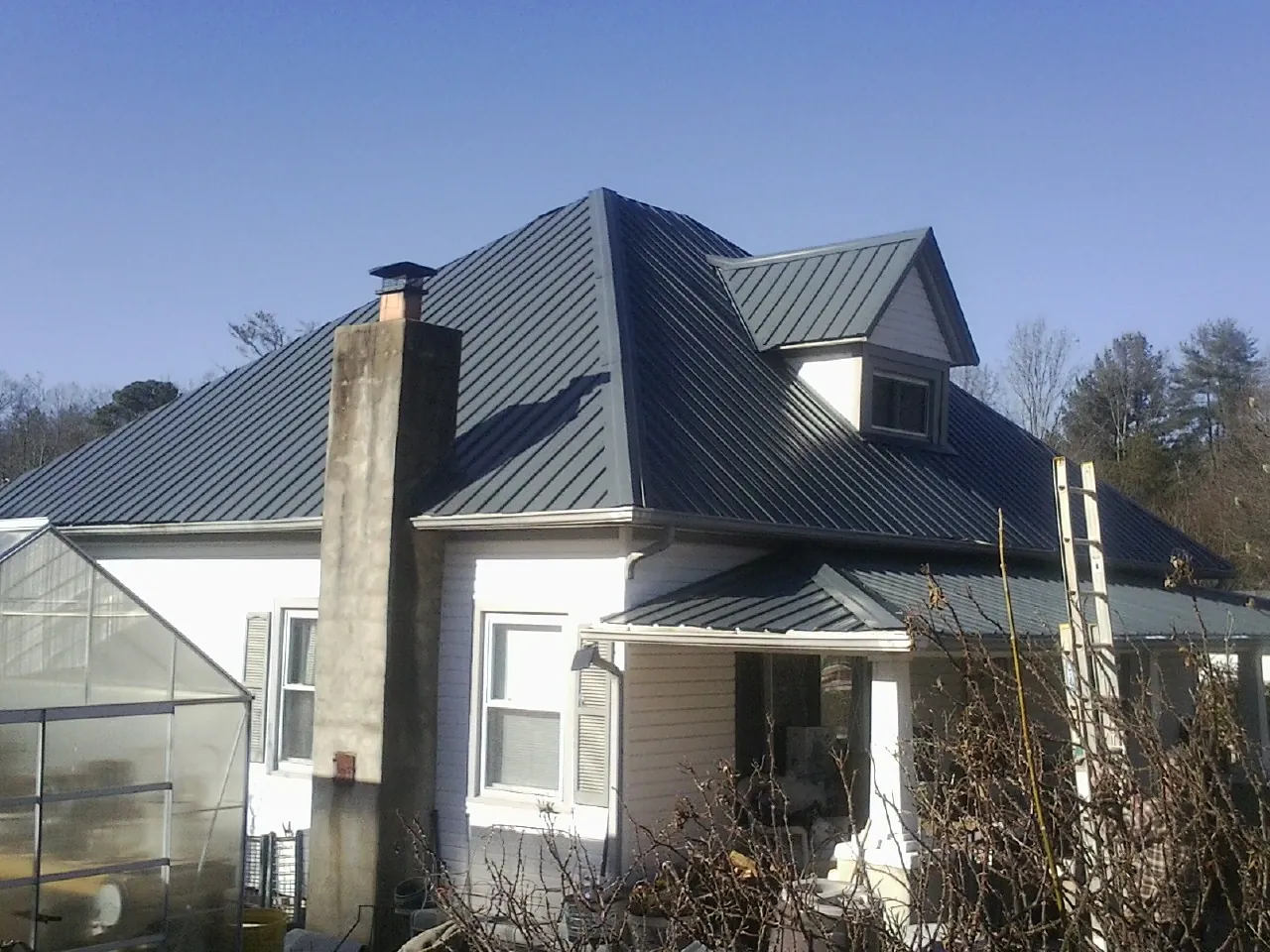 Dark blue standing seam metal roof on a white farmhouse with dormer — Slate & Tile Roof Repair by Roofing Brothers in Topsfield