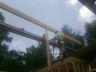 Carpenter setting a ridge beam over a new addition frame — Ice Dam Removal by Roofing Brothers in Topsfield