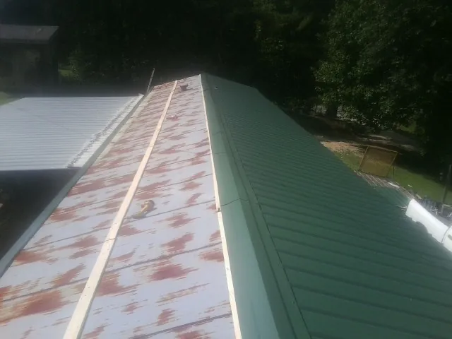 Old rusted panels beside newly installed green metal roofing — Wind Damage Roof Repair by Roofing Brothers in Topsfield