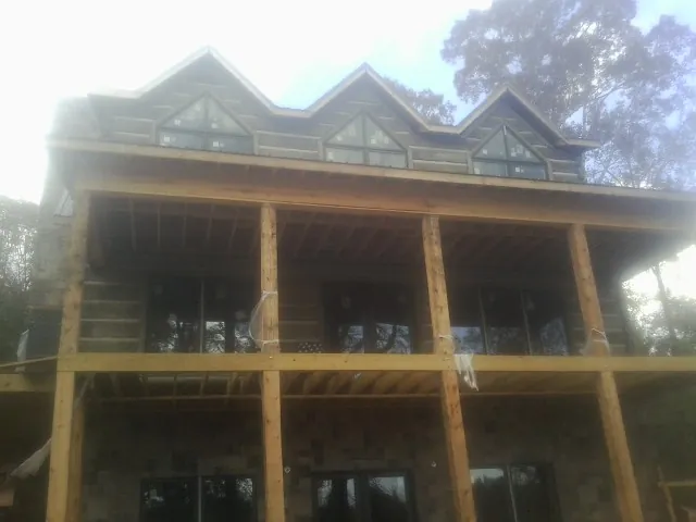 Dormers and porch framing on a large log home under construction — Roof Coating work by our crew in Topsfield