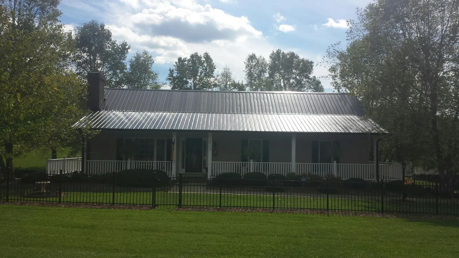Gray metal roof on a brick ranch with a full width front porch — Gutter Guard Installation work by our crew in Topsfield
