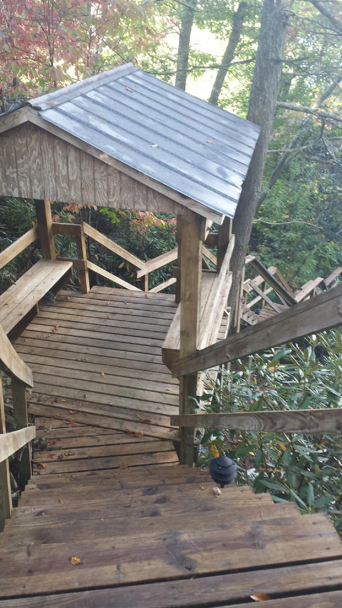 Metal roofed shelter over wooden steps on a wooded walkway — Skylight Repair & Installation work by our crew in Topsfield