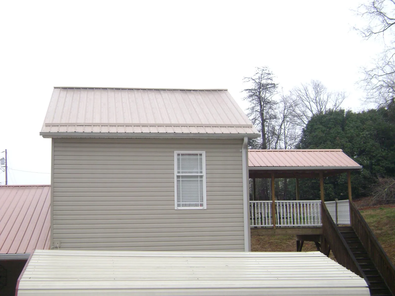Tan metal roofs on a two story addition and attached porch, from a Roof Replacement job in Topsfield