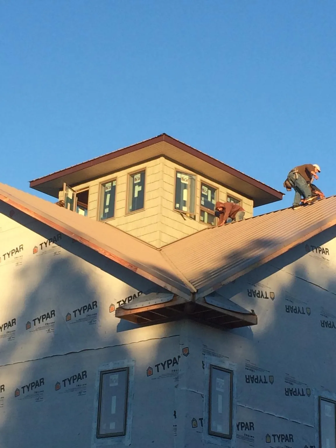 Roofers working around a rooftop cupola on a new metal roof at sunset — Roof Waterproofing in Topsfield by Roofing Brothers